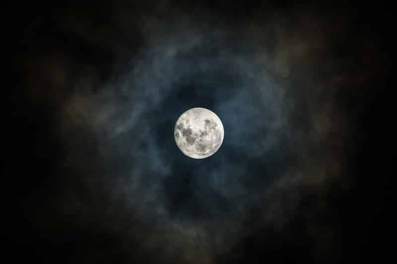 Photo de la Pleine Lune entourée de nuages.