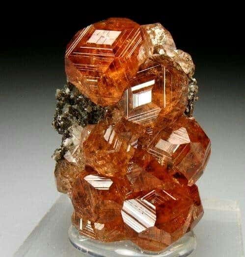 Photo d’un amas de grenat hessonite orange, dont les cristaux sont de forme dodécaèdre