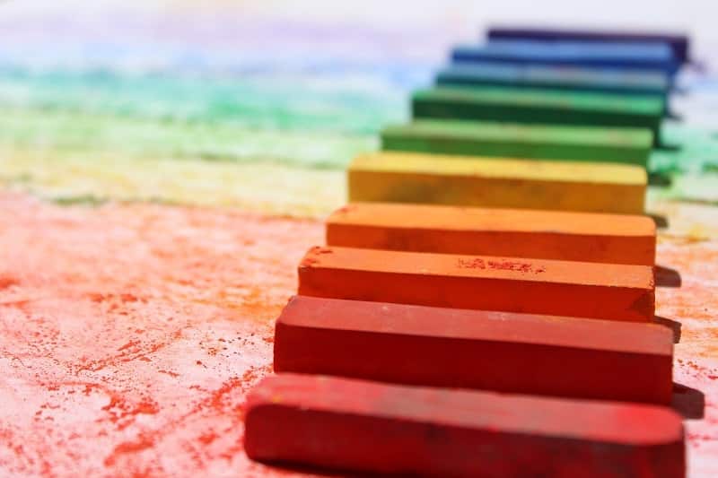 Sur une surface colorée sont disposés parallèlement des craies ou pastels colorées, du rouge au bord de l'écran jusqu'au violet, en passant par le orange, jaune, vert et bleu.