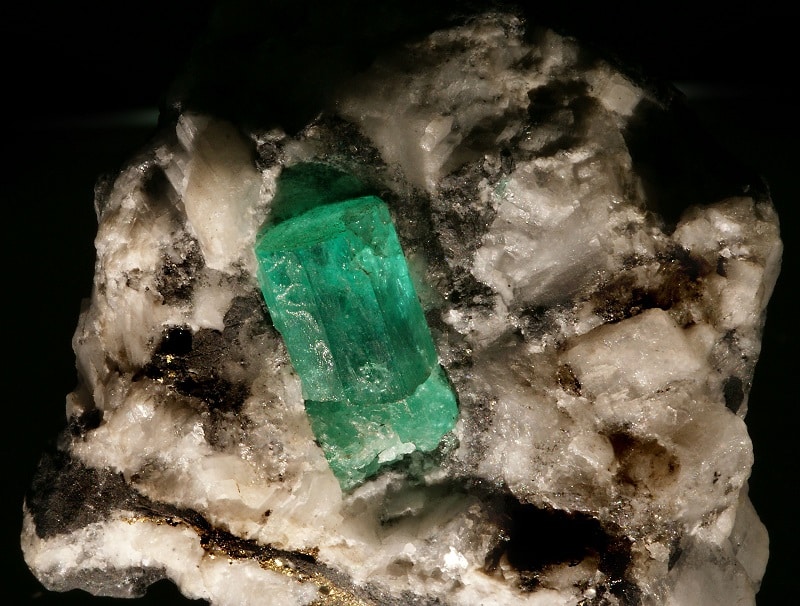 Cristal d’émeraude de 2 cm incrusté dans la roche hôte, de couleur blanchâtre.