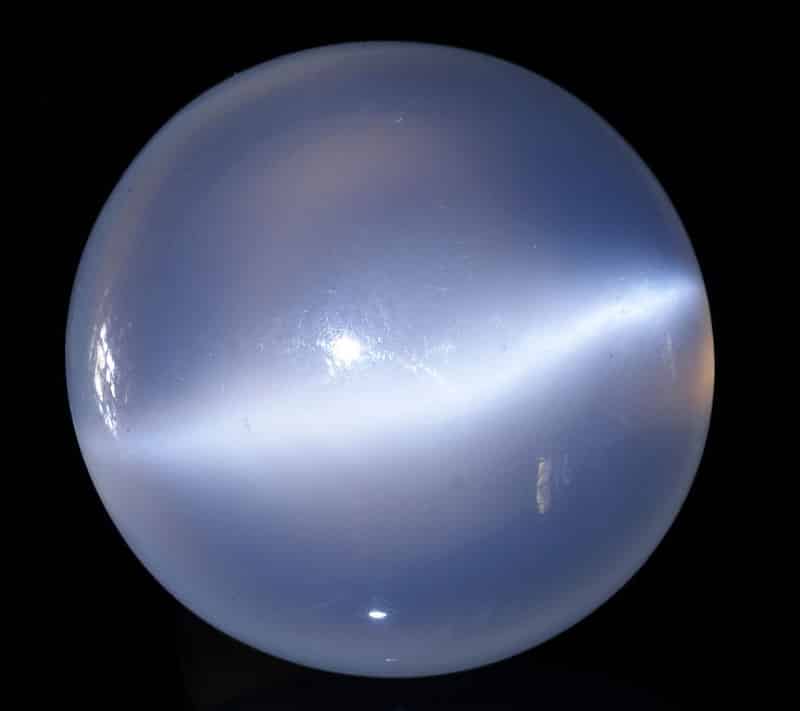 Cabochon de pierre de lune, de 23 millimètres de diamètre, de couleur bleuté irisé.
