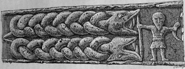 Relief sculpté montrant un homme bras tendus, tenant une corne et une lance et faisant barrage à un montre double formé d’entrelacs.